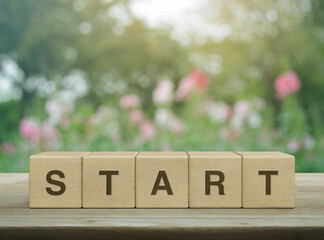 Start letter on wood block cubes on wooden table over blur pink flower and tree in park, Business...