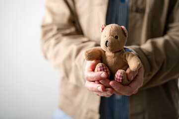 Person carefully holding bear toy in hands and giving it