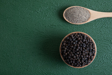 Ground black pepper with grains of black pepper on a green background,top view