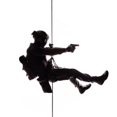 Silhouette of police officer in tactical gear descending from a height, rope exercises with...