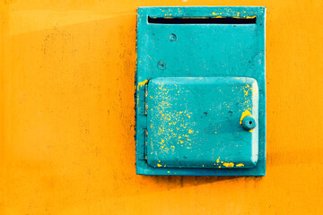 Old painted turquoise mailbox on a bright yellow texture surface, fresh pastel colors.  Pastel trendy background