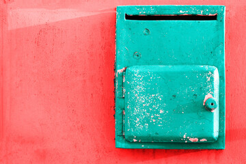 Old painted turquoise mailbox on a bright pink texture surface, soft pastel colors. Pastel trendy background
