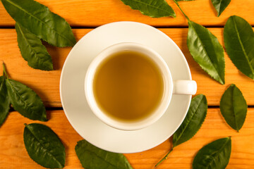 A glass cup of green tea, tea leaves  on wooden background