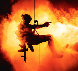 Silhouette of police officer in tactical gear descending from a height, rope exercises with...