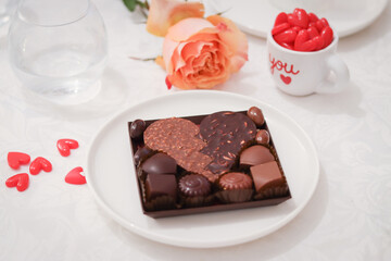 Close up of dark and milk chocolate with almond in a heart shape in a plate with little mini heart and mug wrote with letter 