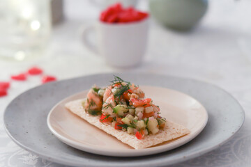 A plate of mixed vegetables salad such cucumber, bell peppers, shallot and dill leaves with shrimp toasted on crispy cereal bread with vinaigrette dressing. Light illumination and mini red heart 