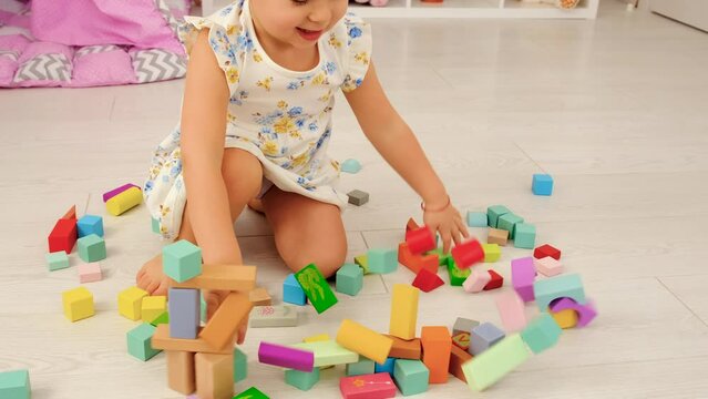 The child plays in the children's room with a wooden constructor. Selective focus.