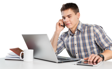 Happy young man works on his laptop with coffee at the table