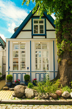 Facade of old Germany house, white windows, blue sky, flowers. Rostock.