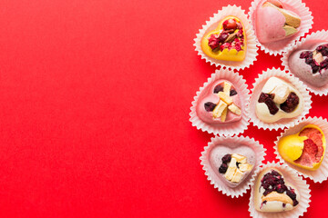 chocolate sweets in the form of a heart with fruits and nuts on a colored background. top view with space for text, holiday concept