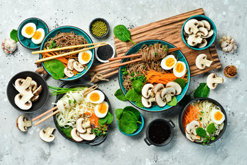 A set of Asian dishes with noodles. Udon and soba noodles. On a concrete gray background. Top view.