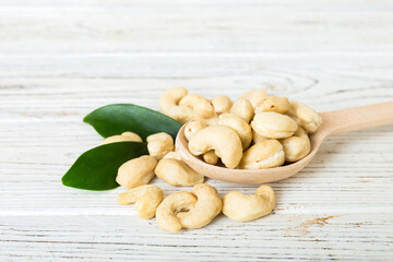Cashew nuts with green leaves in spoon on table background, Healthy food