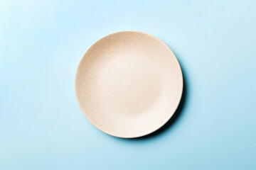 Top view of isolated of colored background empty round beige plate for food. Empty dish with space...