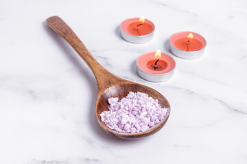 Obraz na płótnie Canvas Lilac bath salts in wooden spoon. Bath salt and candles