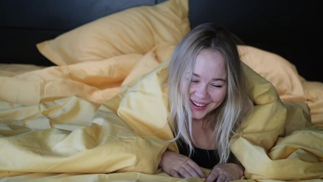 Portrait of a contented woman under a blanket. Beautiful blonde gets sexual satisfaction in bed