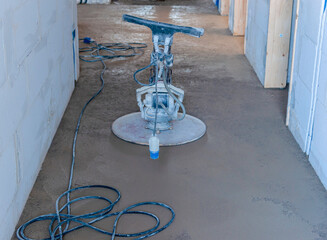 Ramming and grinding of semi-dry floor screed by a machine with a rotating disk for leveling.