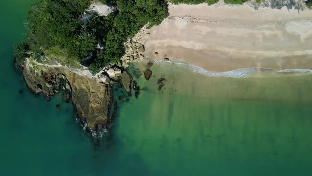 Aerial view of isolated hidden beach on summers day with rocky cove.
