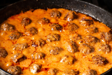 Cooking homemade meatballs in a frying pan in a sauce of tomatoes and sour cream. Close-up macro. Food background.