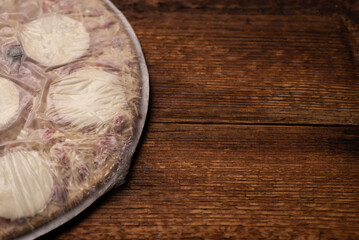 Frozen pizza on a wooden background. Semi-finished pizza packed in film.