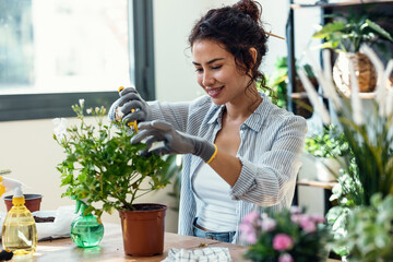 Beautiful smiling woman arranging plants and flowers in a greenhouse