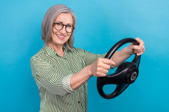 Photo of mature retired business woman wear striped green shirt driving steering wheel insurance company ad isolated on blue color background
