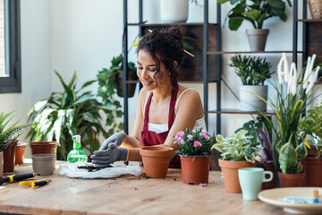 Influencer woman arranging plants and flowers while recording a tutorial video with smartphone in a greenhouse