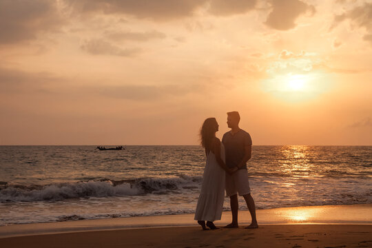 Silhouettes lovely couple in love enjoying honeymoon summer on tropical sandy beach at sunset background. Man and woman happy couple holding hands. Family travel vacation concept. Copy ad text space