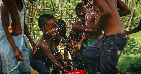 A Group Of African Children, Laughing and Playing with Water in Rural Area. Black Kids Celebrating Life with Joy. Camera Captures Beauty Of Childhood, Innocence and Purity of Live in Village - obrazy, fototapety, plakaty