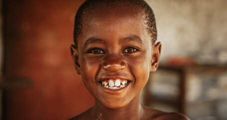 Close up portrait of a Cute Little African Kid with a Big Beautiful Smile Looking at the Camera. Happy Male Child in a Rural Area Representing Innocence, Peace and Hope. Documentary Footage