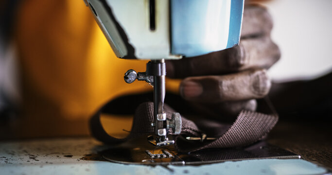 Close Up Footage of an Old Sewing Machine and Black Male Hands Working on it to Fix a Belt. Talented Male Tailor Doing his Job Professionally as He Sews a Customer's Piece of Clothing