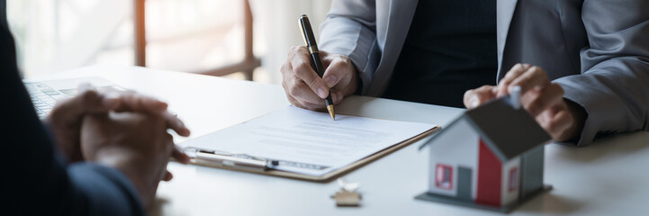 Young Asian home sales agents, insurance agents, and real estate agents offer young Asian entrepreneurs information on price conditions when signing a contract to buy rent house in the office.