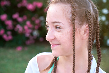Cute teen girl with freckles and pigtails smiling outdoors in summer.