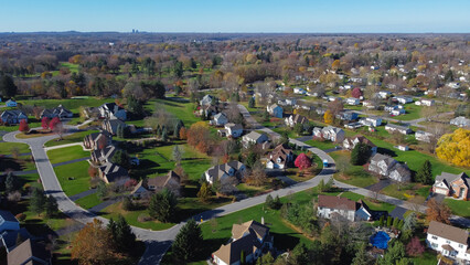 Aerial view master planned low density single family residential houses with grassy yards landscaping and Rochester Downtown buildings in far distance, Upstate New York, USA