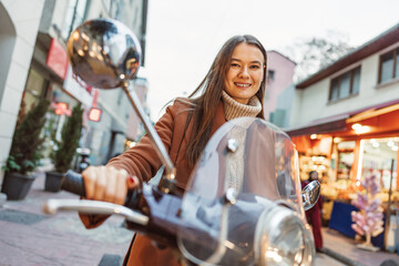 Portrait of attractive young cheerful woman riding moped scooter