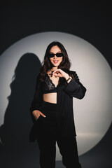 Young elegant stylish woman in a black suit. Studio shot. A woman in a black suit and black glasses on a white background