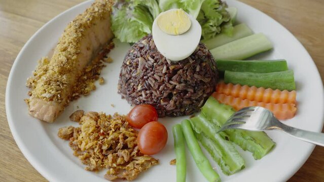 Fried salmon fish with riceberry (Riceberry is a rice variety from Thailand) and vegetable, healthy food style.