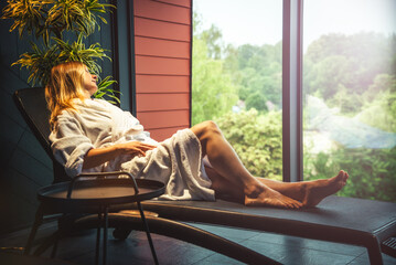 Woman in white bathrobe lying on sofa and relaxing at home.