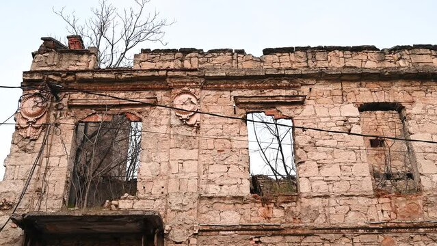 Holes of bullets and shells in the wall on the front line. Remnants of the war. Destroyed and burned building.