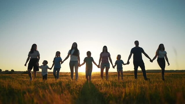 community large family in the park. a large group of people holding hands walking lifestyle silhouette on nature sunset in the park. big family kid dream concept. people in the park. large family