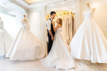 Portrait of smiling cheerful happy love asian couple fashion bride man and woman posing in white wedding dress for pre wedding hug together at wedding interior fashion studio