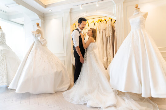 Portrait of smiling cheerful happy love asian couple fashion bride man and woman posing in white wedding dress for pre wedding hug together at wedding interior fashion studio