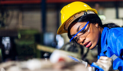 Professional labor machanic engineer technician worker industrial african black woman wearing blue safety uniform working control with heavy machine in manufacturing  factory production line.industry