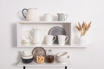 foreground view, close-up of open kitchen shelves with porcelain and ceramic utensils. stylish kitchen background in white tones.