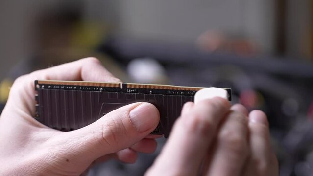Extreme close-up of unrecognizable professional repairman male cleaning memory RAM connectors with eraser on blurred background. Concept of desktop PC maintenance and service. Shooting in slow motion.
