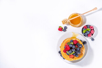 Healthy summer morning breakfast pancakes with fresh berry. Stack of traditional pancakes with blueberry, raspberries, honey. Healthy morning breakfast on white sunny background