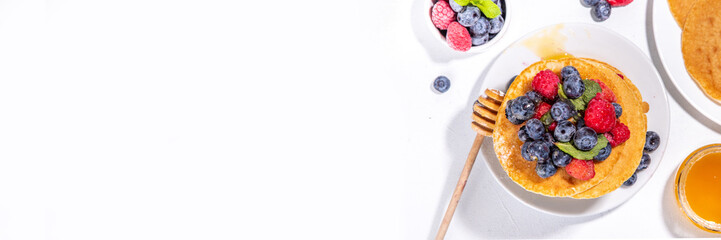 Healthy summer morning breakfast pancakes with fresh berry. Stack of traditional pancakes with blueberry, raspberries, honey. Healthy morning breakfast on white sunny background