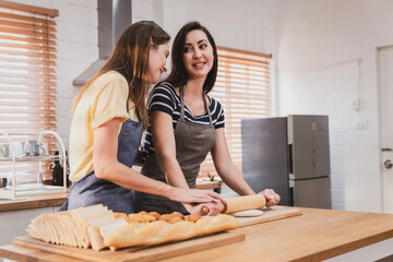 Female and female or LGBT couples are happily cooking bread together in the home kitchen.
