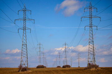 high voltage poles on an agricultural field against the blue sky