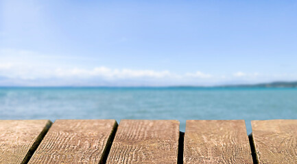 Empty brown wooden table top with blur navy blue sea, ocean and sky background. Mock up for display...