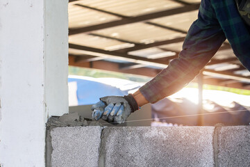 masonry worker make concrete wall by cement block and plaster at construction site